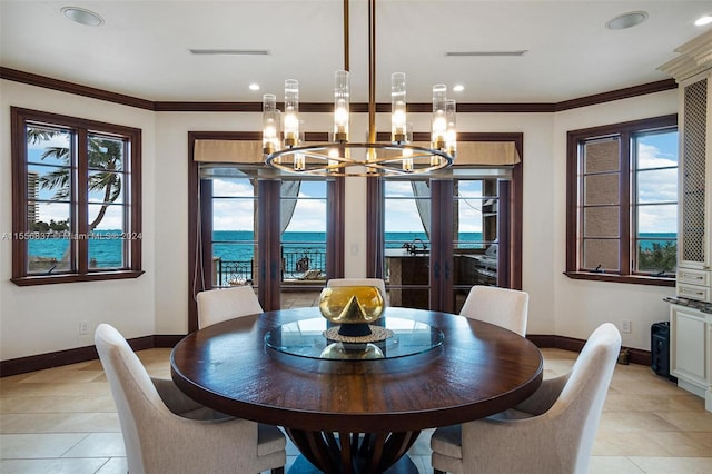 tiled dining area with an inviting chandelier, ornamental molding, french doors, and a water view