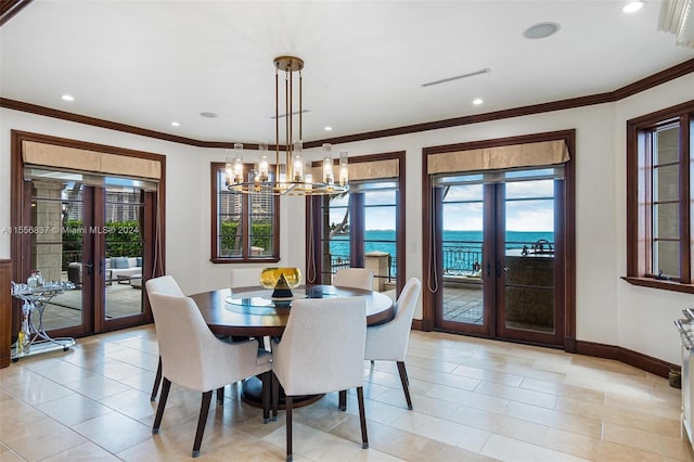 dining room with a chandelier, light tile floors, french doors, crown molding, and a water view