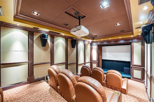 home theater room with a raised ceiling, carpet flooring, and ornamental molding