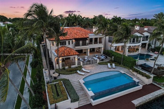 pool at dusk featuring a patio