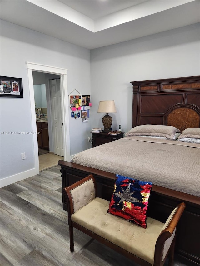 bedroom featuring connected bathroom and light hardwood / wood-style floors