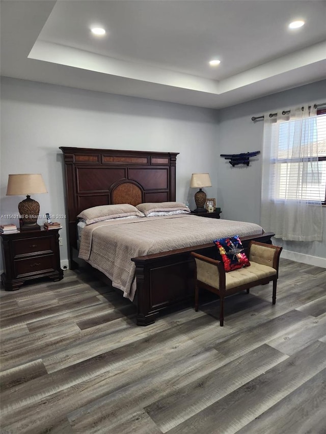 bedroom with dark hardwood / wood-style floors and a raised ceiling