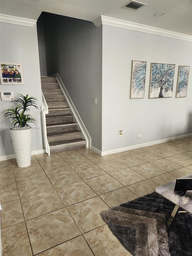 stairs with light tile floors, a textured ceiling, and crown molding