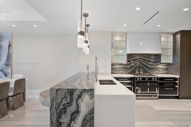 kitchen featuring pendant lighting, double oven range, backsplash, custom range hood, and sink