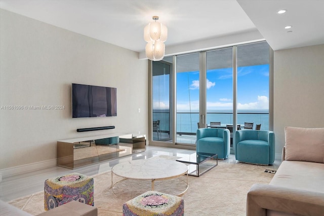 living room with expansive windows, light hardwood / wood-style floors, and a water view