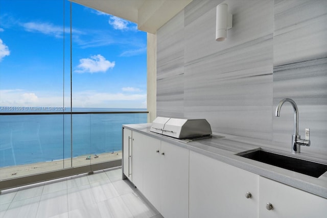 view of patio / terrace with a water view, a balcony, and sink