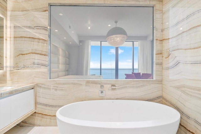 bathroom featuring vanity, a bathtub, a water view, and tile walls