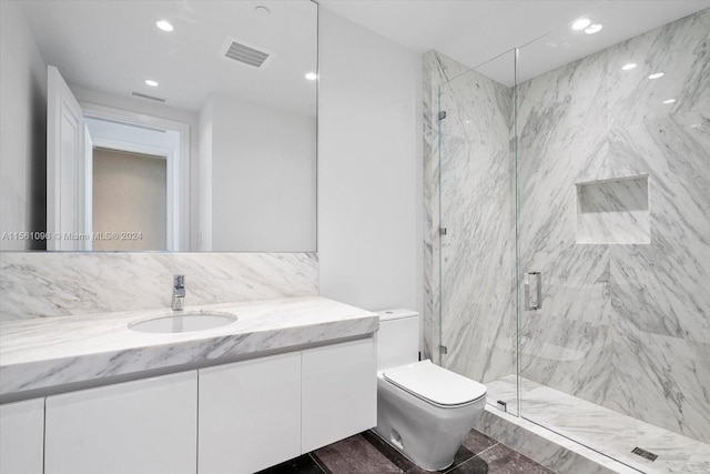 bathroom featuring tile walls, toilet, vanity with extensive cabinet space, a shower with shower door, and tile flooring