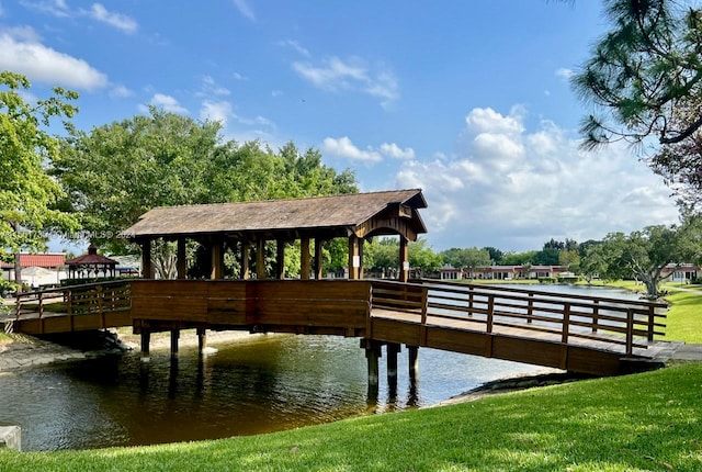 dock area featuring a gazebo, a water view, and a lawn