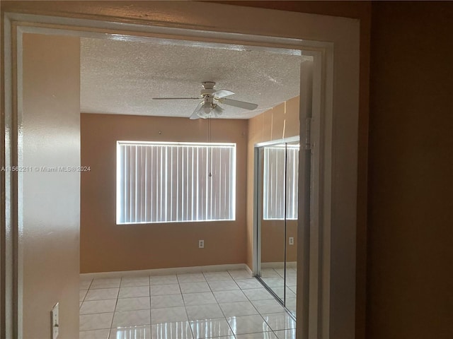 tiled empty room featuring a textured ceiling and ceiling fan