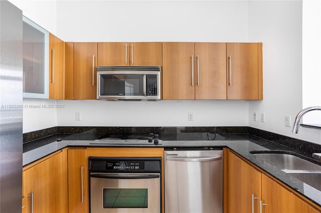 kitchen featuring dark stone countertops, appliances with stainless steel finishes, and sink