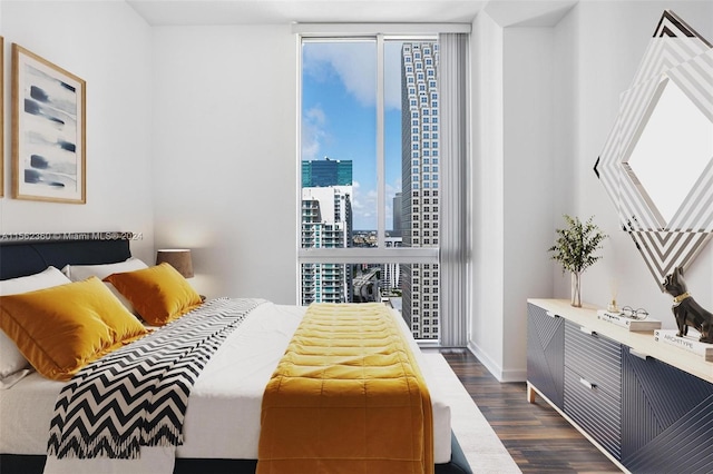 bedroom with a wall of windows, multiple windows, and dark hardwood / wood-style flooring