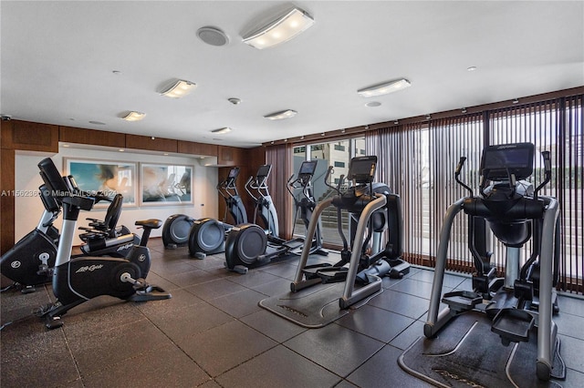 workout area with a healthy amount of sunlight, wood walls, and dark tile floors