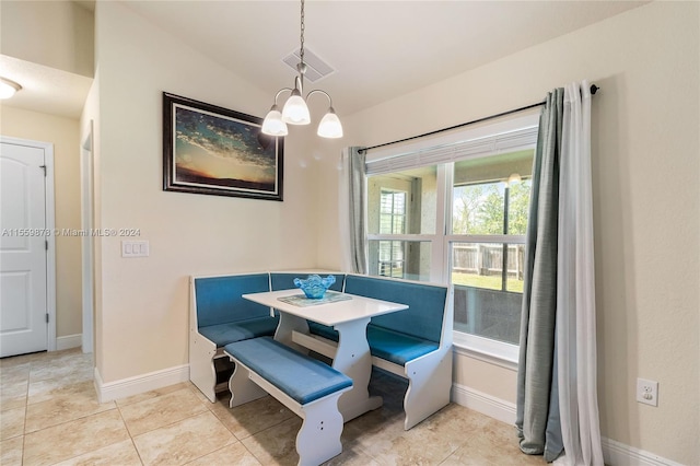 tiled dining room featuring an inviting chandelier and lofted ceiling