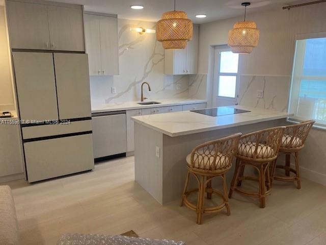 kitchen with white refrigerator, light hardwood / wood-style flooring, stainless steel dishwasher, sink, and black electric cooktop