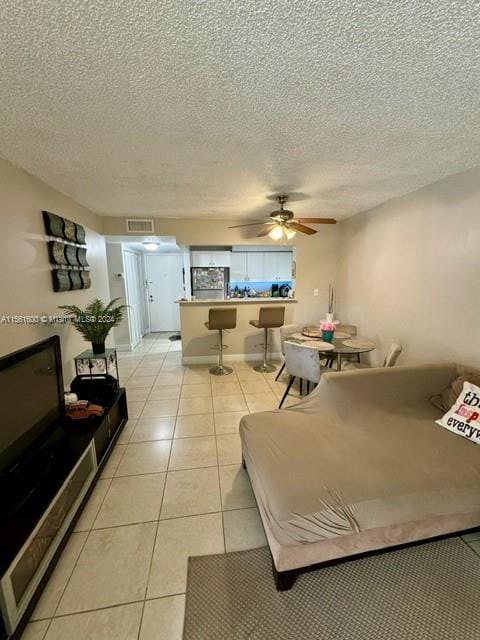 tiled bedroom featuring ceiling fan, a textured ceiling, and refrigerator