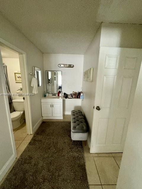 corridor featuring light tile floors, a textured ceiling, and sink