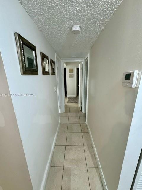 corridor featuring light tile flooring and a textured ceiling