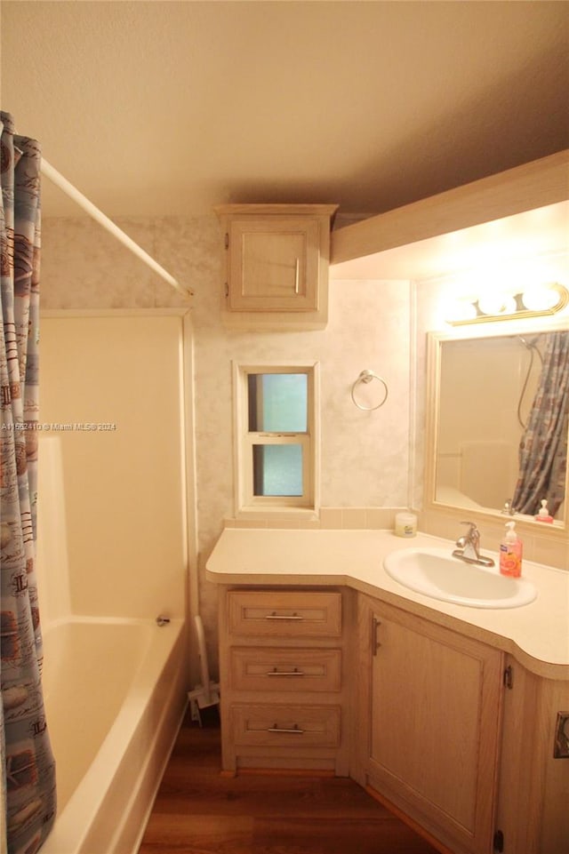 bathroom with hardwood / wood-style flooring, shower / bath combo with shower curtain, and vanity