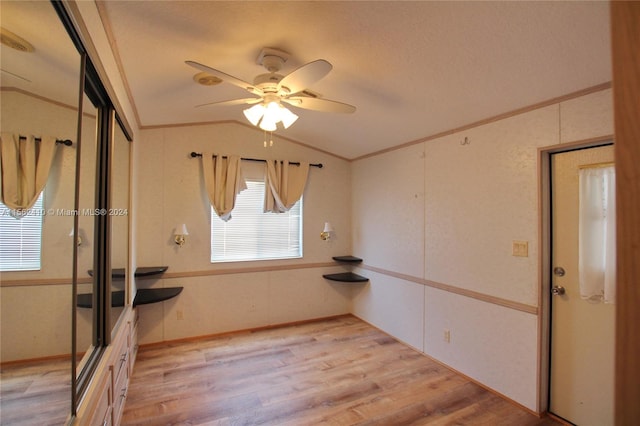 empty room with lofted ceiling, ceiling fan, and light wood-type flooring