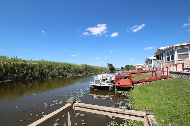 dock area featuring a deck with water view and a yard