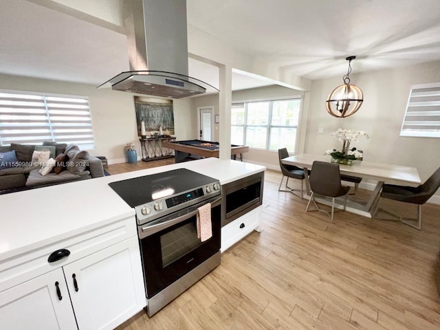 kitchen featuring pendant lighting, light hardwood / wood-style floors, stainless steel appliances, island range hood, and white cabinetry