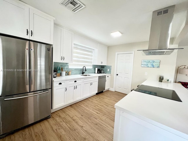 kitchen with white cabinets, appliances with stainless steel finishes, light hardwood / wood-style floors, island range hood, and tasteful backsplash