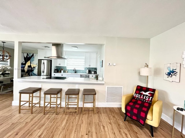 kitchen featuring white cabinetry, light hardwood / wood-style floors, appliances with stainless steel finishes, and island range hood