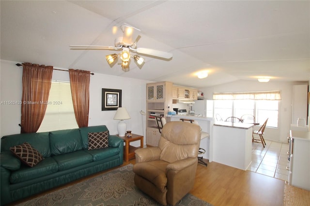 living room with ceiling fan, light hardwood / wood-style flooring, and vaulted ceiling