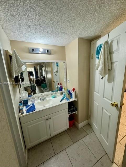 bathroom with a textured ceiling, tile flooring, and vanity