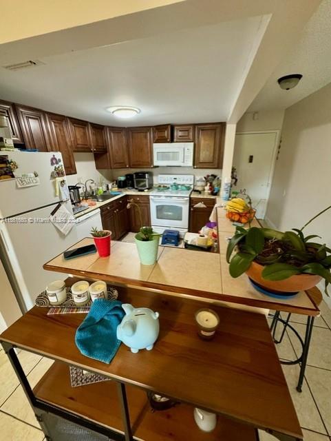 kitchen with white appliances, sink, and light tile floors