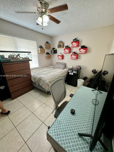 tiled bedroom featuring ceiling fan and a textured ceiling