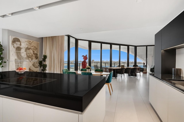 kitchen with white cabinets, a kitchen island, light tile floors, and a wall of windows