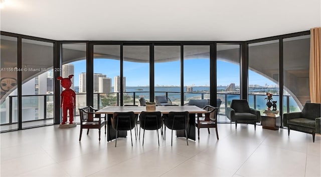 dining space with a water view, light tile floors, and a wall of windows