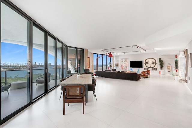 living room featuring floor to ceiling windows, a water view, and light tile flooring