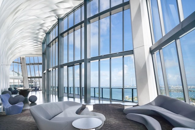 living room with floor to ceiling windows, a water view, and a wealth of natural light