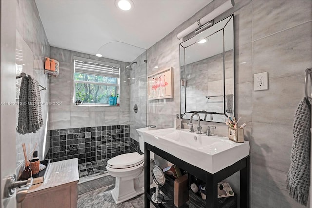 bathroom featuring toilet, vanity, tile walls, and tiled shower