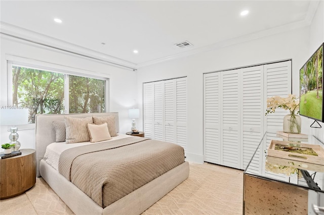 bedroom featuring multiple closets and crown molding