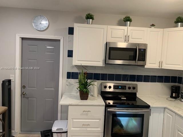 kitchen featuring light stone counters, appliances with stainless steel finishes, backsplash, and white cabinetry