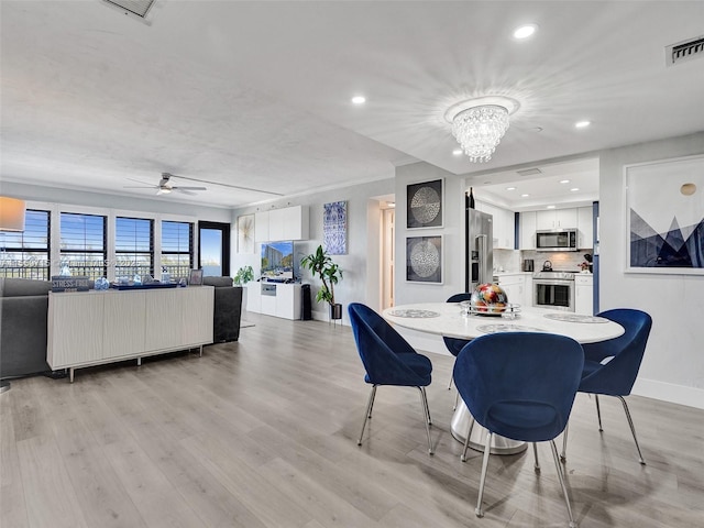 dining area featuring light hardwood / wood-style flooring and ceiling fan with notable chandelier