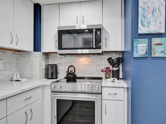 kitchen with decorative backsplash, white cabinets, stainless steel appliances, and light stone counters