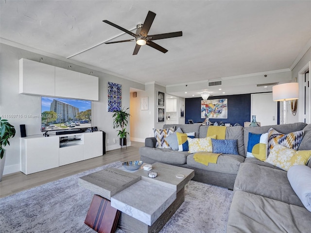 living room with ceiling fan, ornamental molding, and light wood-type flooring