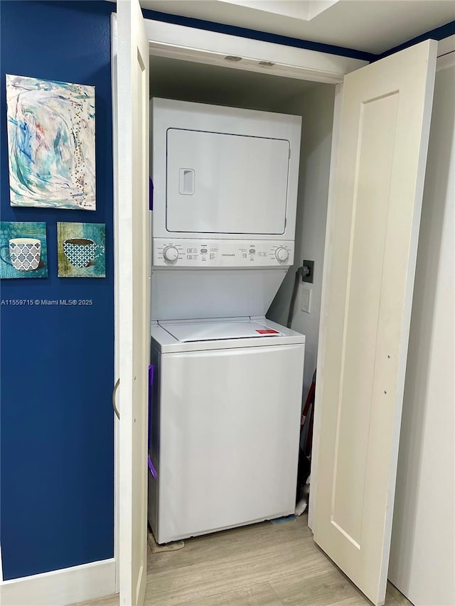 laundry area featuring light hardwood / wood-style floors and stacked washer / drying machine