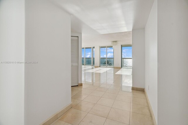 hallway with light tile patterned floors and a wall of windows