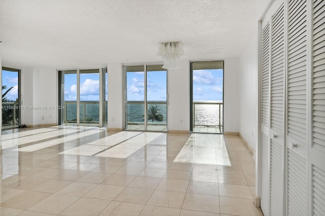 interior space featuring a textured ceiling, a water view, and floor to ceiling windows