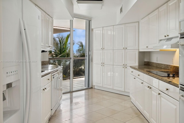 kitchen with white appliances, custom exhaust hood, light tile patterned flooring, and white cabinetry