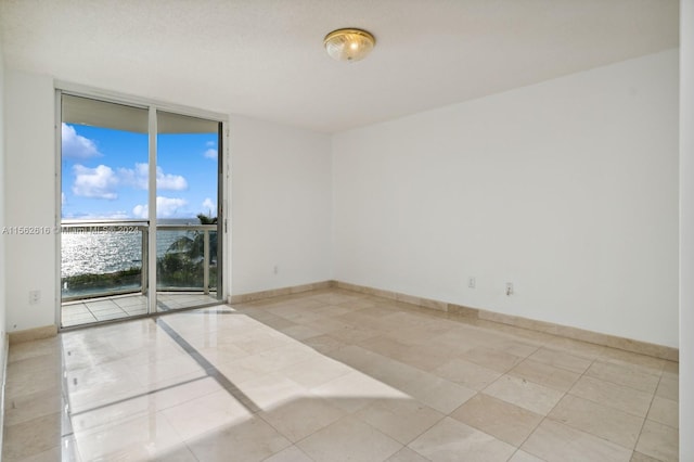 tiled spare room featuring a water view and a wall of windows