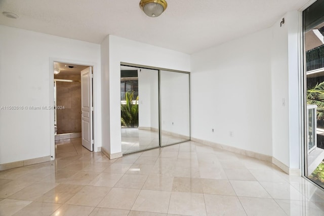 unfurnished bedroom with connected bathroom, light tile patterned floors, and multiple windows