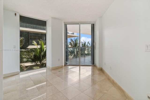 tiled empty room with a textured ceiling and floor to ceiling windows