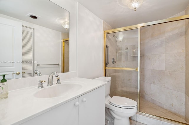 bathroom with a shower with shower door, vanity, toilet, and tile patterned flooring